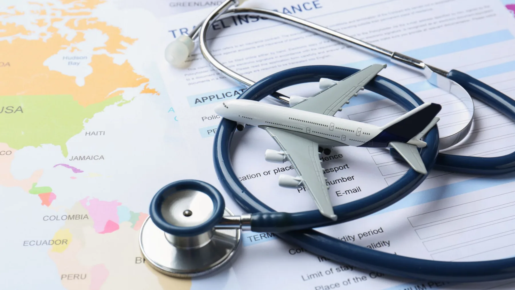 Avião em miniatura sobre um estetoscópio, documentos e mapa, ilustrando o seguro viagem para a Argentina e a assistência médica durante viagens internacionais.