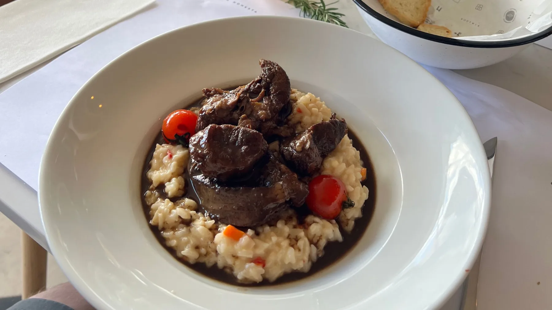 Prato de carne sobre risoto cremoso, acompanhado de tomates-cereja e molho, no restaurante Bohemia Bistró, em Colonia del Sacramento, Uruguai.