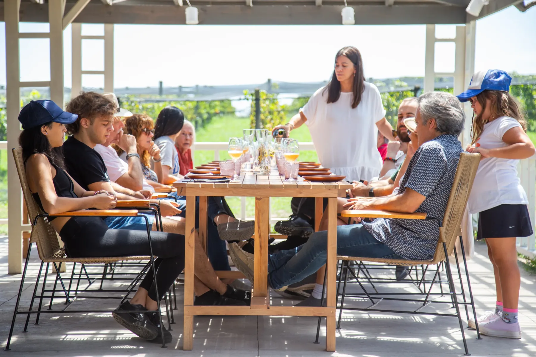 Degustação de vinhos na Vinícola Gamboa, com grupo reunido à mesa em frente aos vinhedos.