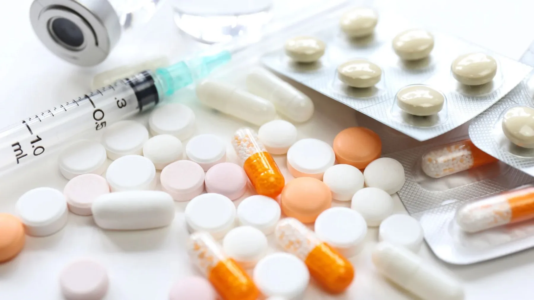 Comprimidos, cápsulas, medicamentos em cartelas e seringa, ilustrando os cuidados para transportar medicamentos em viagens à Argentina.